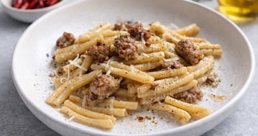 Caserecce pasta with Italian salsiccia sausage, parmesan cheese, and black pepper in a white bowl.