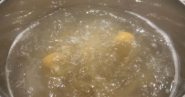 Dry pasta noodles cooking in a stainless steel pot of boiling hot water.
