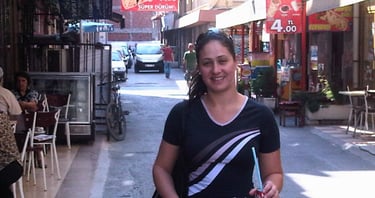 Foto da autora caminhando pelas ruas de Izmir, entre a arquitetura local e o cotidiano da cidade.