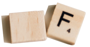 Two wooden Scrabble tiles, one blank and the other with the letter "F" and a score of 4.