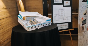Gala photos showcasing model of a future building plan and blueprints