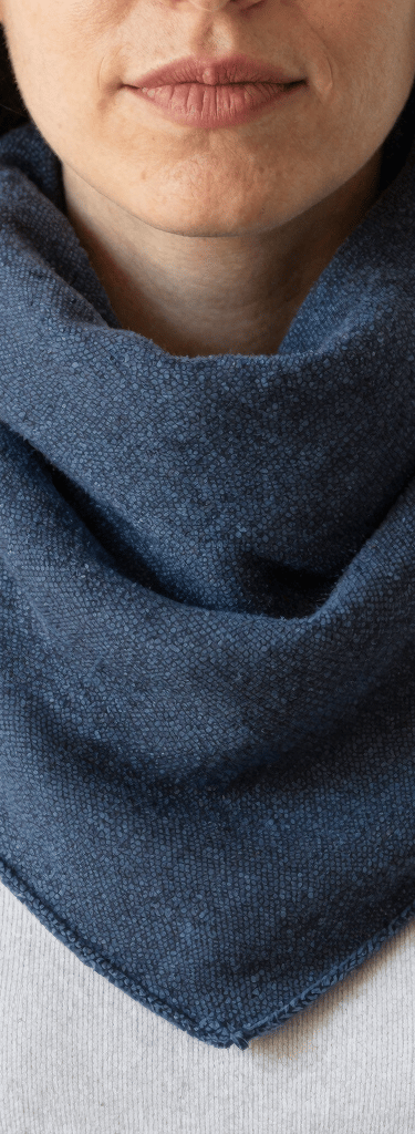 Close-up of a colorful handmade snood scarf draped elegantly on a rustic wooden chair.