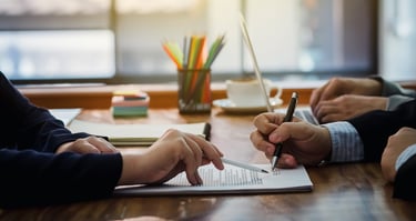a group of people sitting at a table with papers and pens