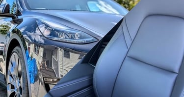 A shinny, mirror like, dark gray tesla and a clean gray tesla front seat 