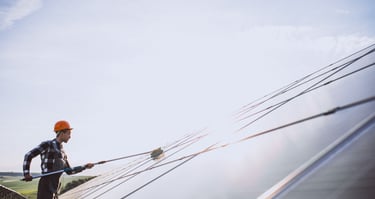 Technicien nettoyant un panneau photovoltaïque à la perche télescopique