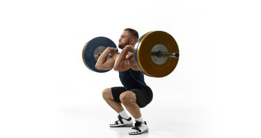 Athletic man performing a heavy front squat with a barbell for strength training on a white background.