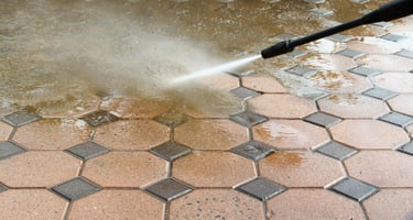 a person using a hose to clean a brick floor
