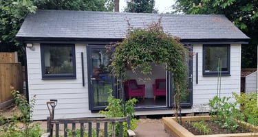 Modern white garden room with black window frames and a climbing plant archway.