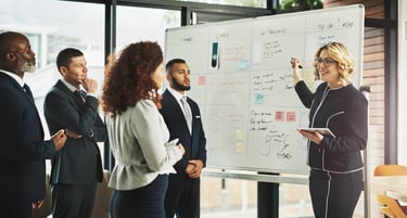 Diverse business team collaborating on project management using a whiteboard in a modern office.