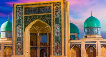 Barak-Khan Madrasah in Tashkent, Uzbekistan, featuring blue tiled domes and Islamic architecture at sunset.