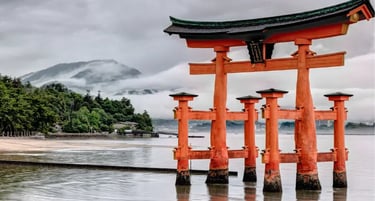 The floating Itsukushima Shrine torii gate in Miyajima, Japan, under a cloudy sky.