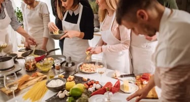 Group of people wearing aprons cooking Italian pasta during a hands-on culinary workshop.