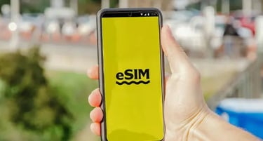 Hand holding a smartphone displaying an eSIM logo on a bright yellow screen outdoors.