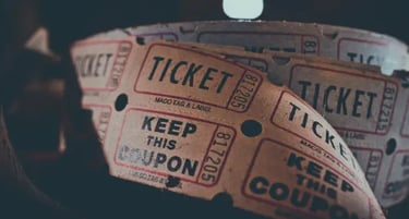 A vintage roll of tan paper raffle tickets and movie coupons with black printed text.