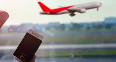 Hand holding a passport and boarding pass at an airport window with a plane taking off.