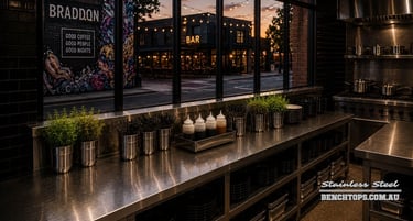 Long workspace counter and durable stainless steel benchtop Braddon looking out to a street at dusk.