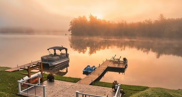 Two docks with boats on a calm lake shoreline.