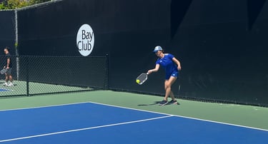 Pickleball player in blue outfit reaching for a low shot during pickleball training match.