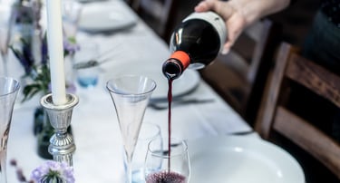 a person pouring wine into wine glasses on a table