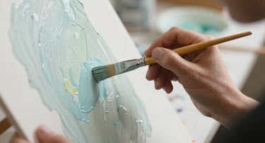 Un artista aplicando pintura acrílica azul claro texturizada sobre un lienzo con un pincel.