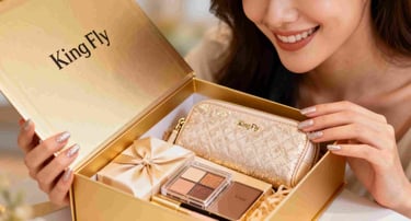 A woman smiling as she unboxes a luxury GWP gift set containing a gold cosmetic pouch.