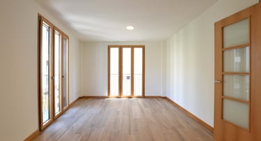 Balconeras de tres hojas mixtas aluminio-madera en salón vacío.