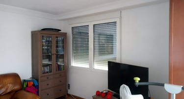 Ventana de dos hojas con persiana en estancia.