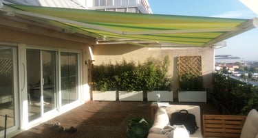 Toldo de brazos extensibles en tonos verdes y amarillos. Terraza atico.