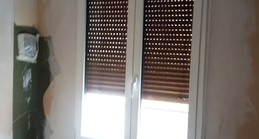 Ventana practicable de 2 hojas con lamas de persiana oscuras.