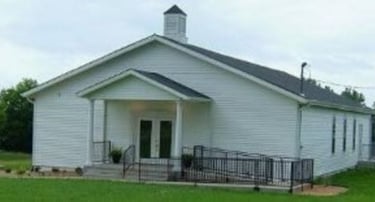 Basehor Church of Christ is a white church building with a black roof and covered porch