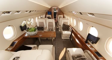 Spacious luxury private jet cabin featuring plush leather seating, elegant wood finishes, and VIP amenities. Designed for eli