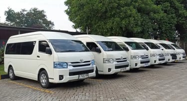 Enam Toyota Hiace warna putih berjajar rapi di tempat parkir pandangan dari kanan depan.