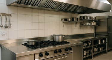 Professional stainless steel commercial kitchen with gas range, ventilation hood, and prep counters 
