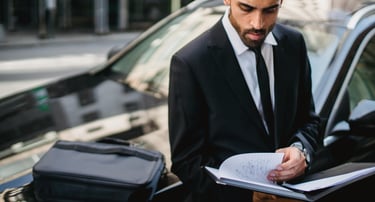 Expert assis sur le capot de sa voiture, travaillant pour aider ses clients à vendre leur véhicule.