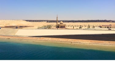 Vista da mesquita com deserto e areia contrastando com o mar ao fundo