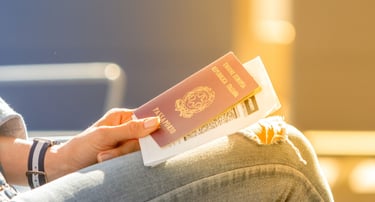 Mão segurando passaporte em terminal de cruzeiro, com malas ao fundo.