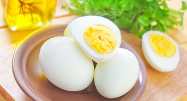 Hard-boiled eggs peeled and sliced on a ceramic plate with fresh parsley garnish.