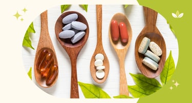 Variety of dietary supplements, vitamins, and herbal capsules on wooden spoons with green leaves.