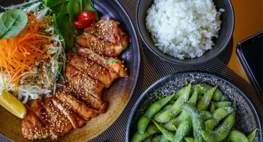 Grilled chicken teriyaki with sesame seeds served with white rice, edamame, and a fresh garden salad.