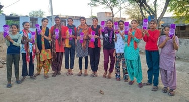 12 girls holding up washable sanitary napkins.