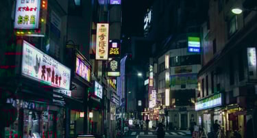 Night view of a bustling Tokyo street with neon signs and storefronts, including a FamilyMart convenience store.