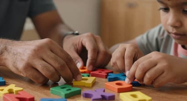 A close-up shot of hands guiding a South Asian / Indian child using colorful wooden phonics letters on a warm wooden table, soft light, cozy coaching studio in Mumbai.
