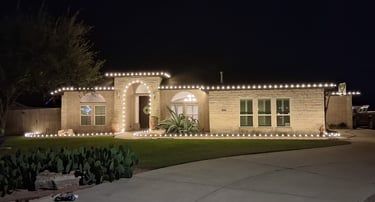 Corpus Christi house at night featuring white outdoor Christmas lights along the roof and landscape.