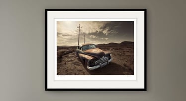 Old rusted classic car with telephone poles and mountains in the background