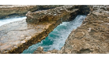 vista de perto da Devil’s Bridge em Antígua com o mar batendo nas rochas abaixo