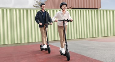 a man and woman riding scooters on a sidewalk