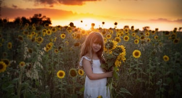 a girl in a white dress holding a bouquet of sunflowers