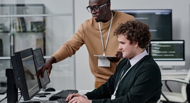 Two diverse IT professionals collaborating on software development at a modern office workstation.