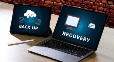 A laptop and tablet showing cloud backup and data recovery icons on their screens.