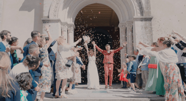Des nouveaux mariés sortent de l'église avec les invités qui jettent des confettis